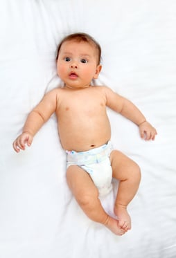 beautiful baby boy portrait lying on bed in diaper